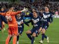 Goalie Paul Izzo is swamped by Victory teammates after his penalty shootout heroics against City. (Will Murray/AAP PHOTOS)